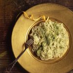 angel hair pasta on a gold plate with a fork
