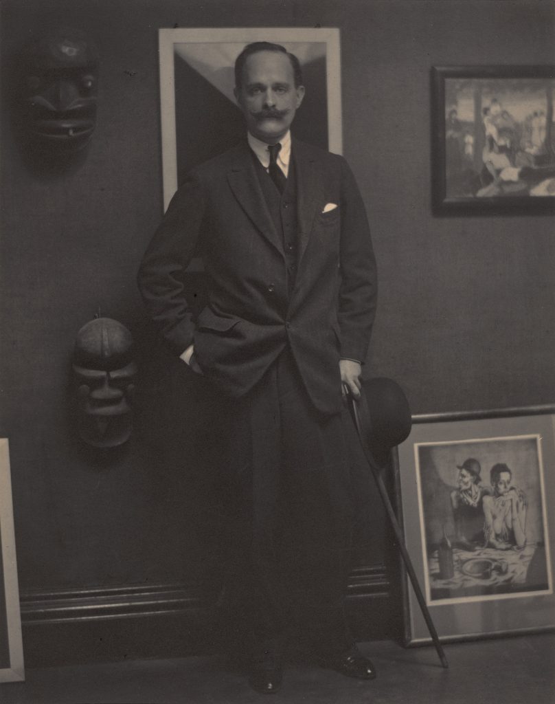 Photograph of a white man with a mustache wearing a suit
