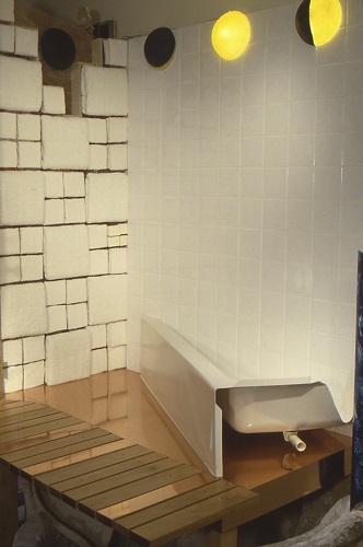 Photo of a room with white tiled walls, half of a bathtub, and other building materials