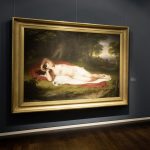 Photo of a painting showing a nude woman laying in the woods