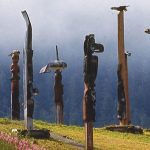 Image of several totem polls with clouds in the background