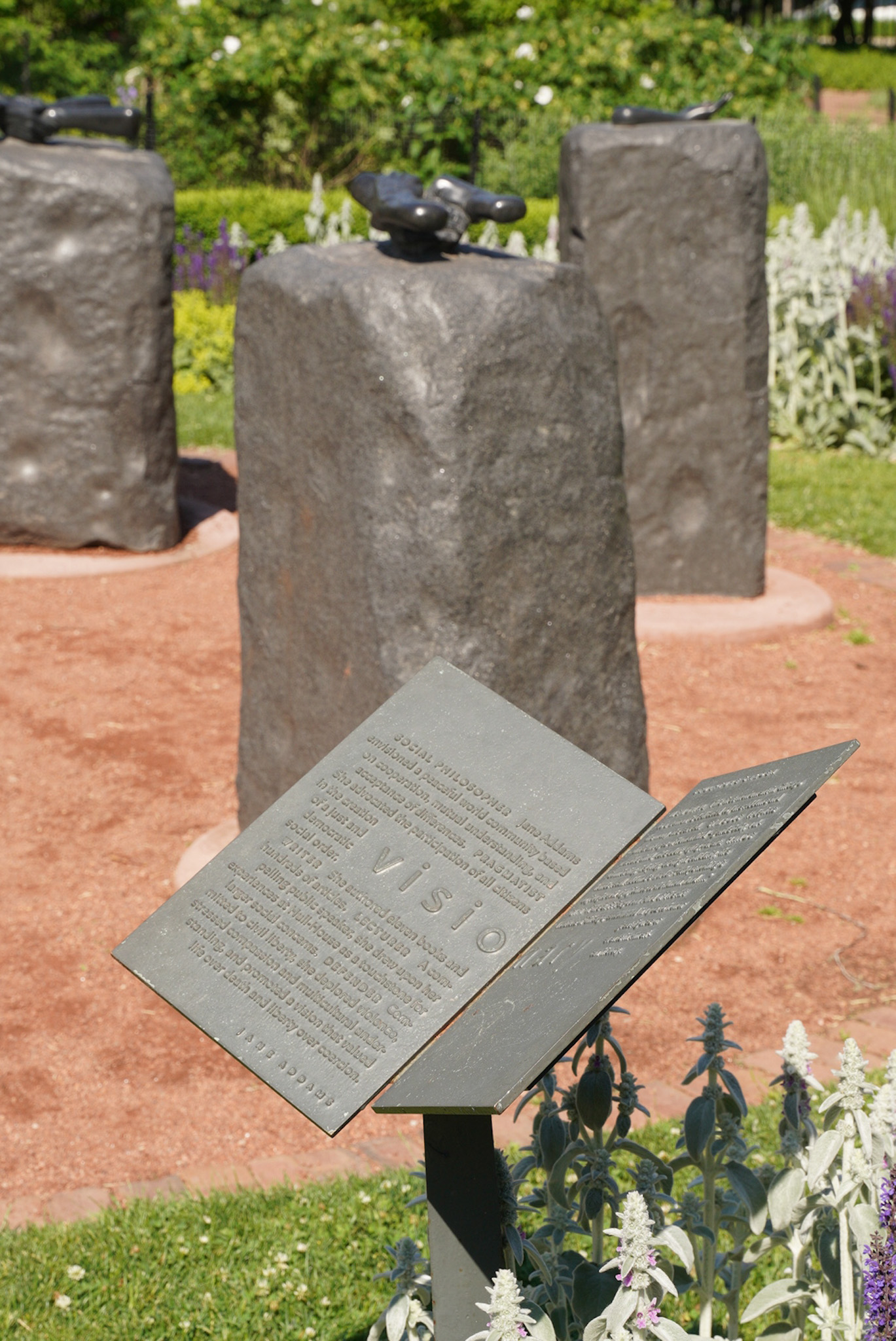 Metal text panel arranged like an open book in front of an abstract stone sculpture