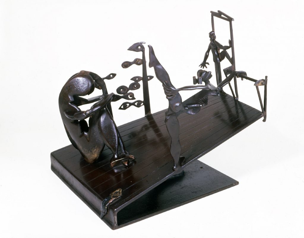 bronze sculpture featuring human-like figures on a tilted plane