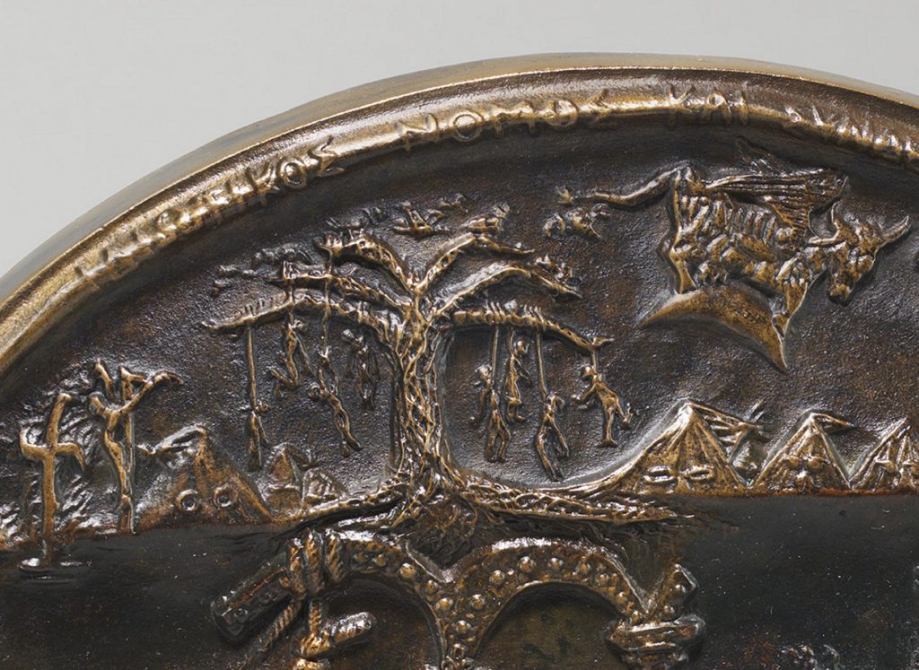 Detail of circular bronze medal featuring lynched figures hanging from a tree