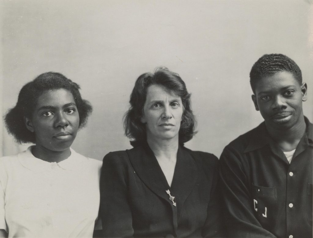 Black and white photograph of a black woman, a white woman, and a black man, seen from the waist up