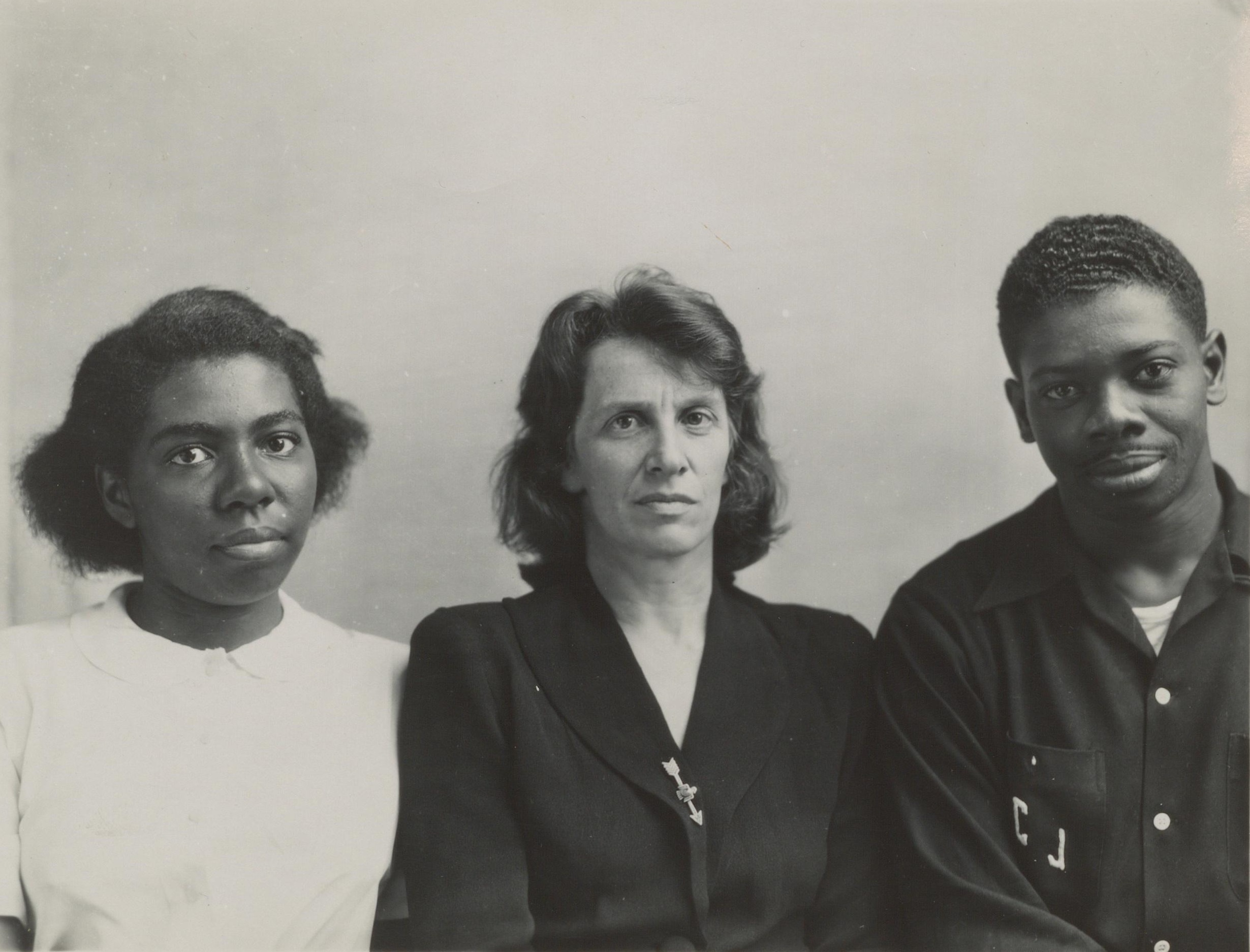 Black and white photograph of a black woman, a white woman, and a black man, seen from the waist up