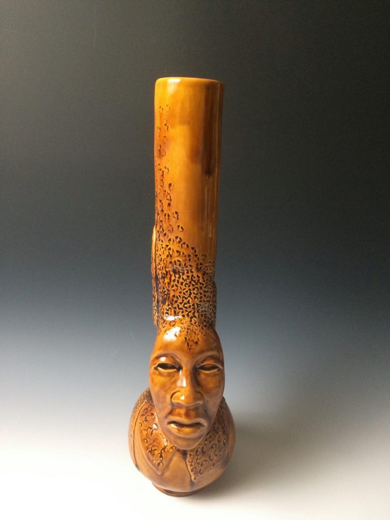 Ceramic vase with a face at the bottom.