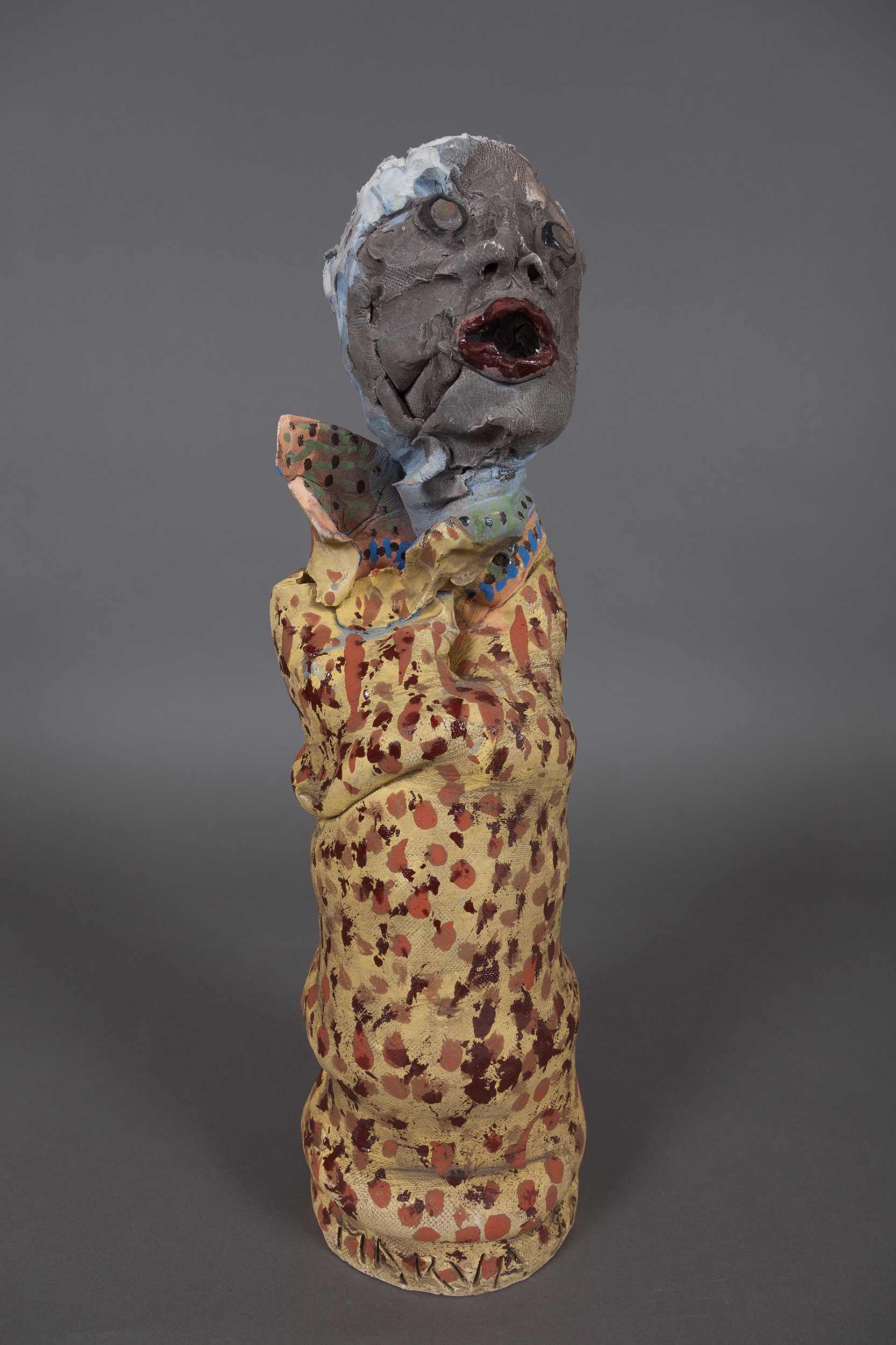 ceramic sculpture with a speckled base and a face-shaped finial