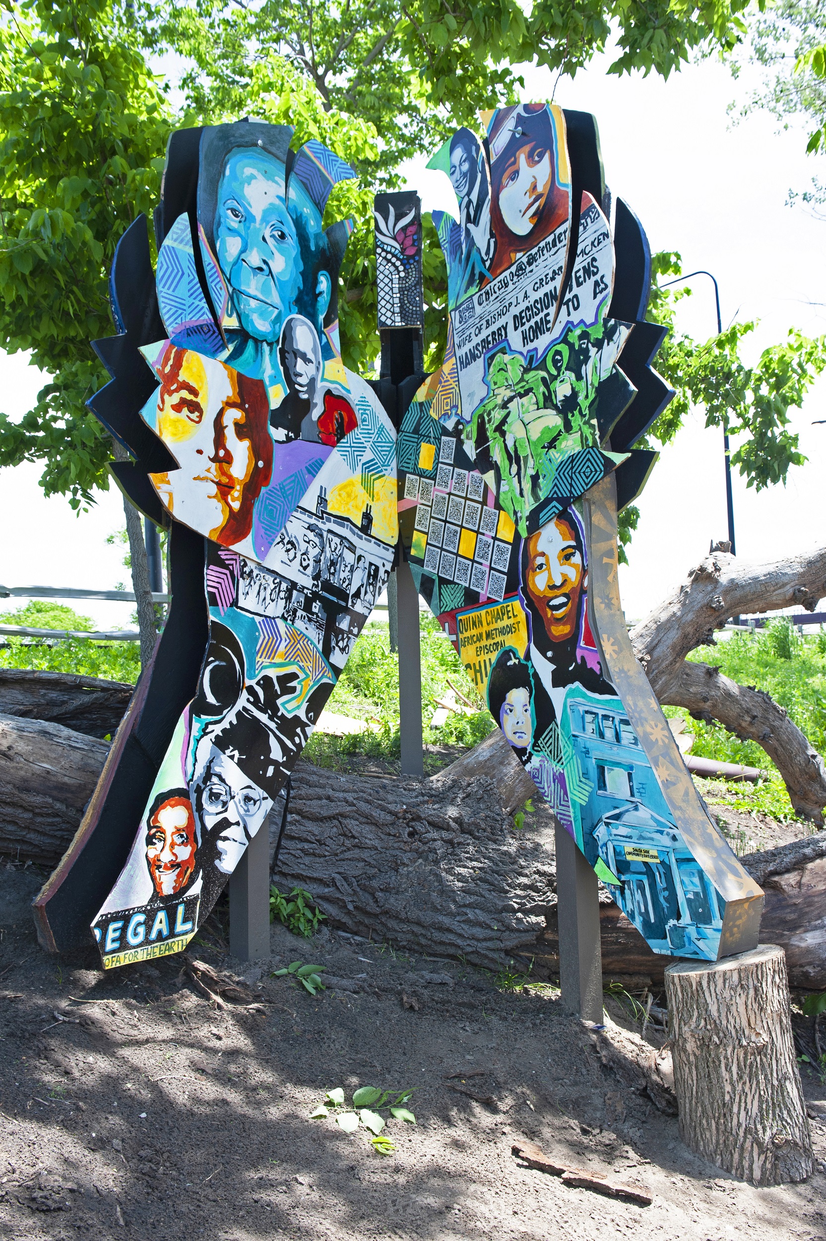 Colorful outdoor sculpture in the shape of wings decorated with various faces