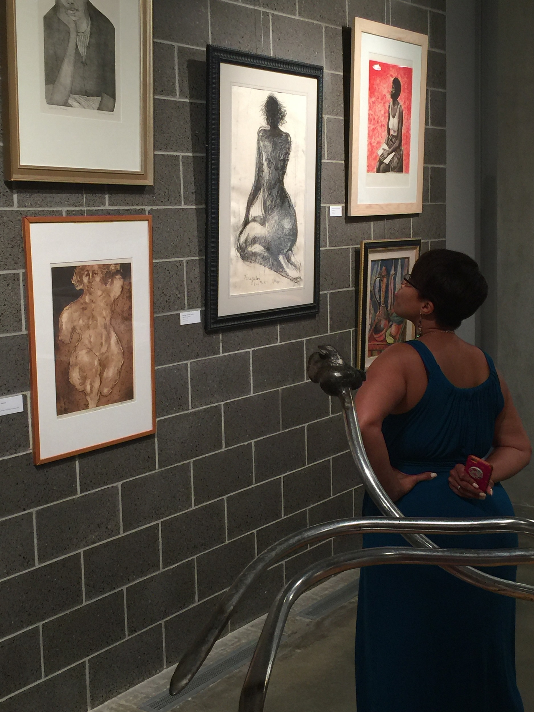 Photograph of African American woman looking at artwork on a gray brick wall