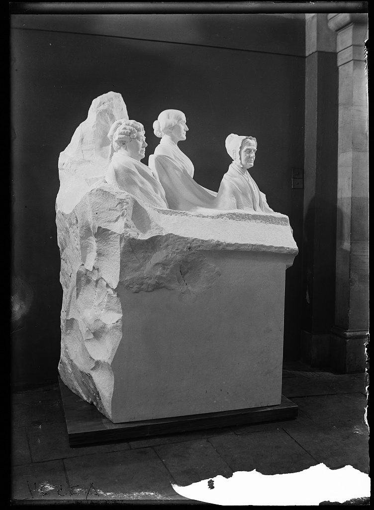 Black and white photograph of unfinished marble statue with three women seen from the waist up