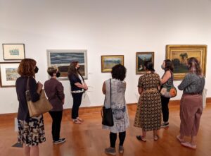 Eight people wearing face masks in a museum gallery, looking at artwork