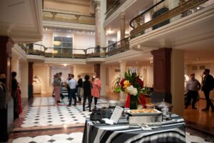 Group of people at a party in a classically inspired interior with a wraparound balcony. Text on the upper story reads LUCE FOUNDATION CENTER