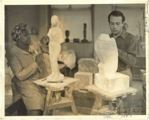 Black-and-white photograph of a Black woman and a white man working together in a sculpture studio