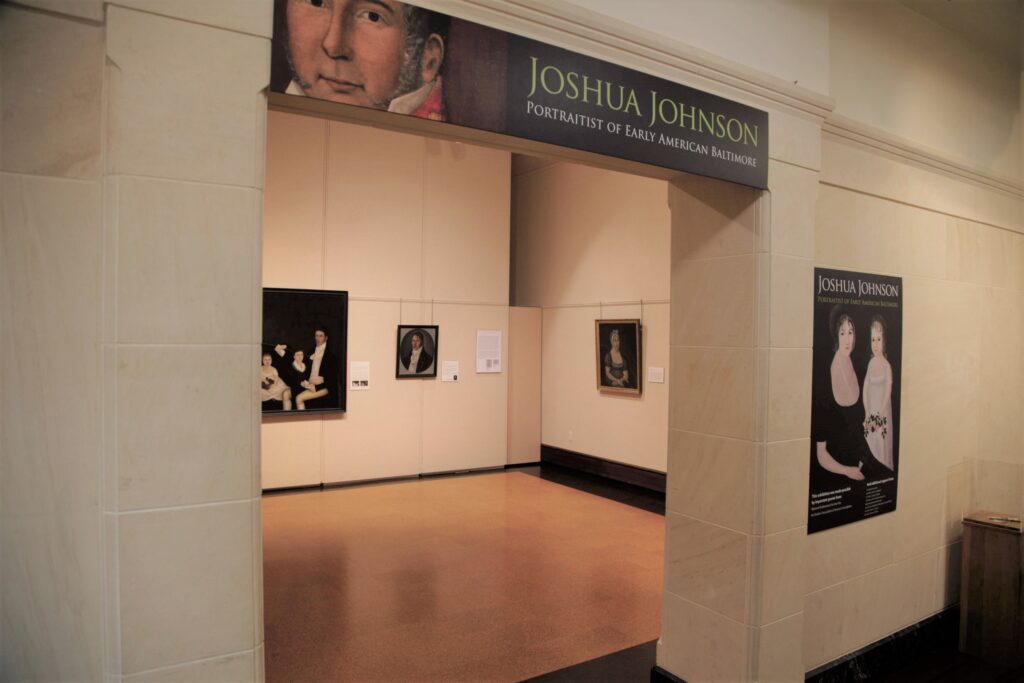 Museum gallery entrance to an exhibition with sign reading JOSHUA JONHSON PORTRAITIST OF EARLY AMERICAN BALTIMORE