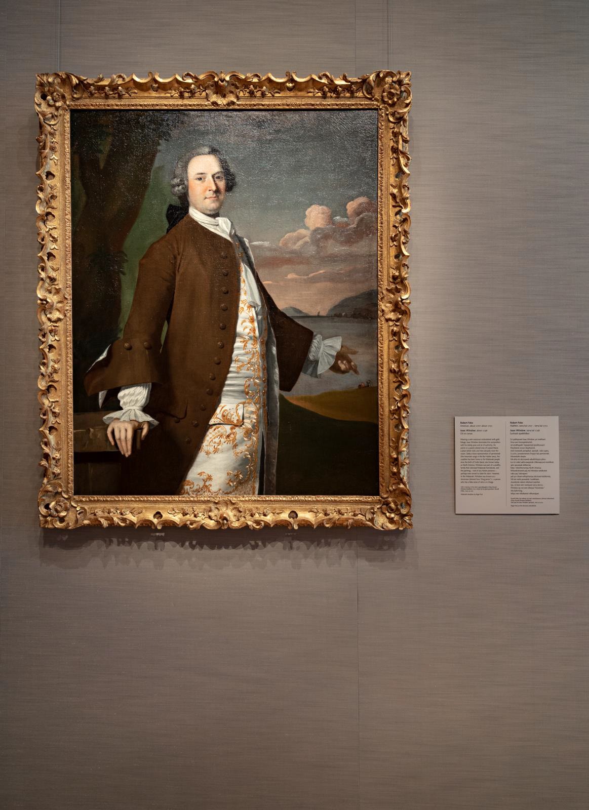 Framed painting of a man in 18th-century clothing hung on the wall of a museum, with an object label printed in two columns to its right