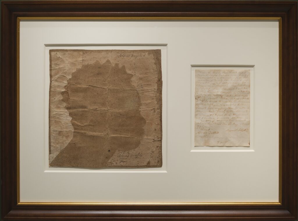 Frame containing a silhouette of an African American woman (fig. 1) on the left and a handwritten document (fig. 2) on the right