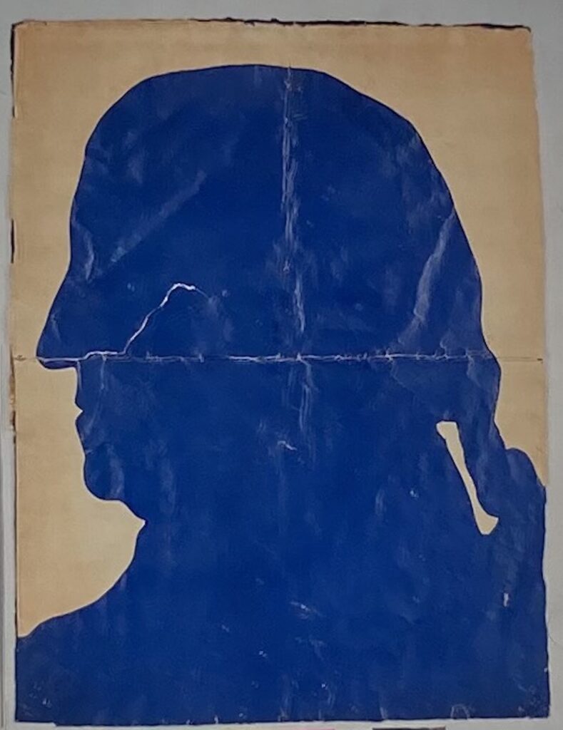 Cut-paper silhouette of a man facing left, rendered in bright blue, with a ponytail at the back of his head.