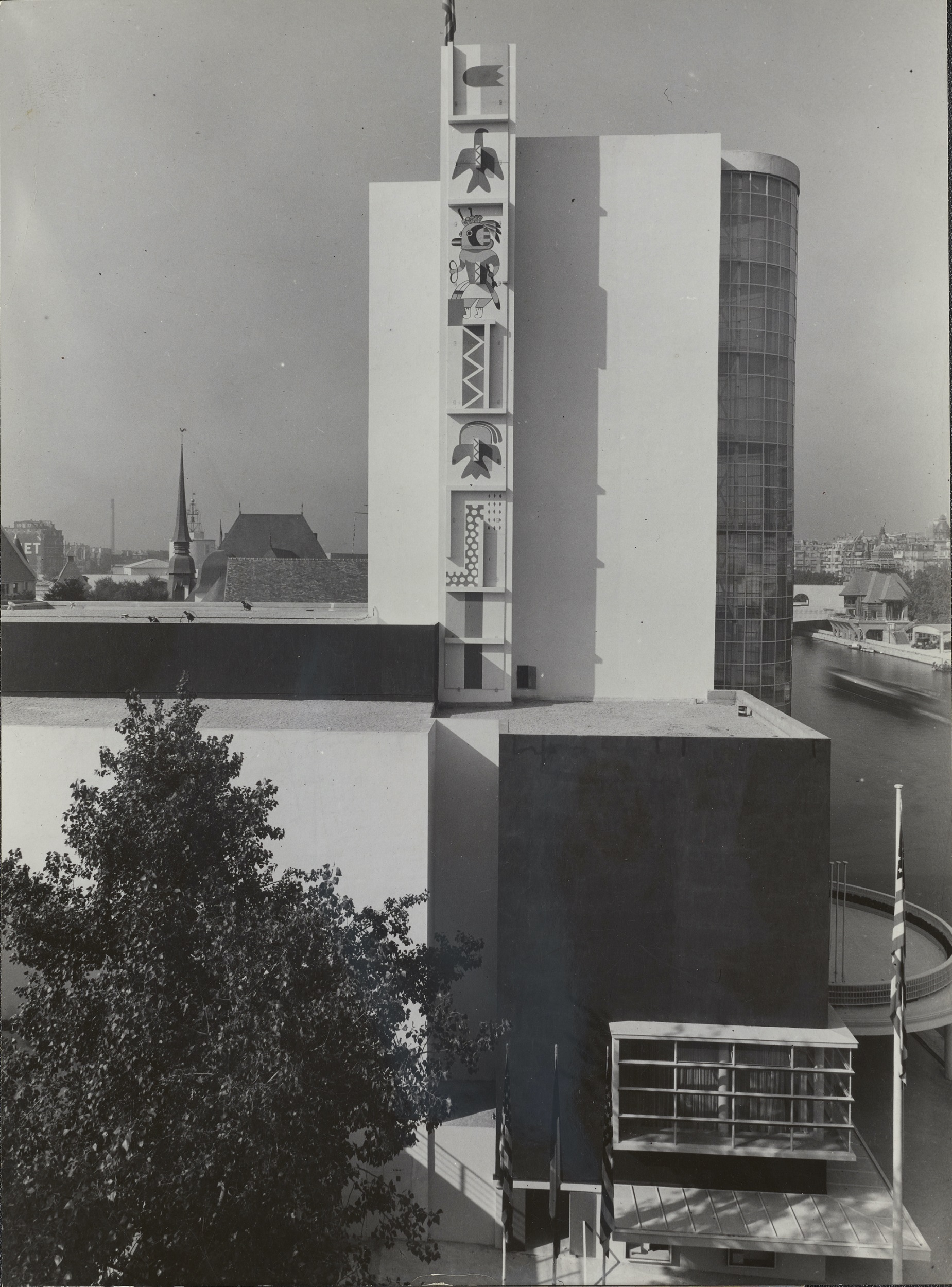 Black-and-white photograph of the architectural work seen in figure 1, but from a different angle highlighting the mural painted along a tall vertical tower