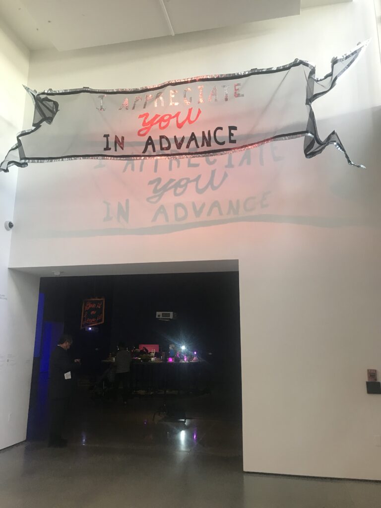 Entrance to a museum gallery with a banner hanging overhead reading "I appreciate you in advance."