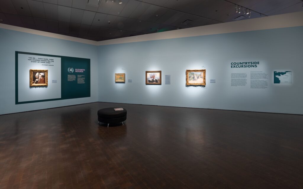 View of the interior of a museum gallery, the walls painted light blue. A framed painting and an interactive display is on the left; three framed paintings and an introductory text titled "Countryside Excursions" is on the right.
