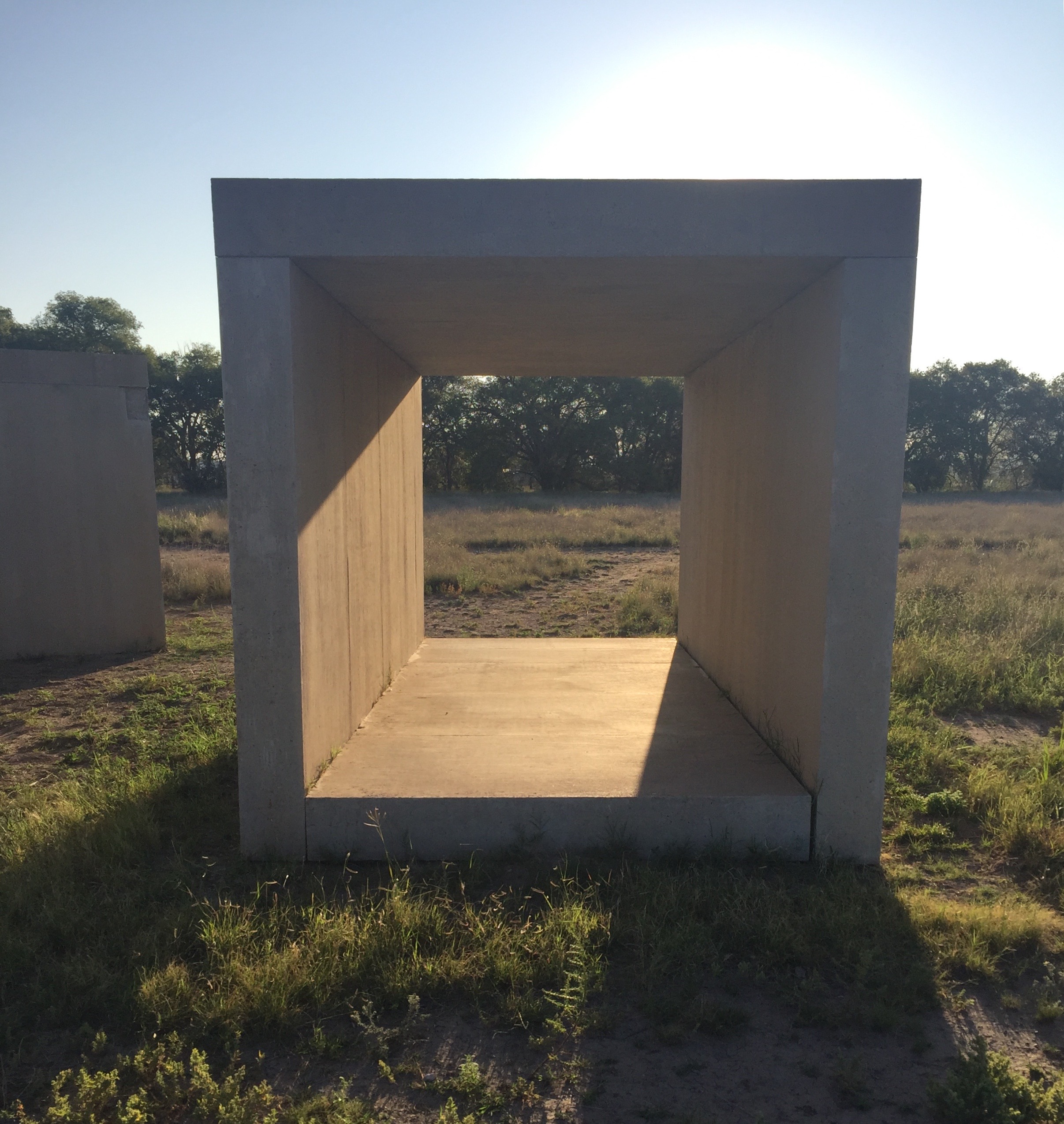 A concrete structure in the form of an open square in a grassy outdoor setting