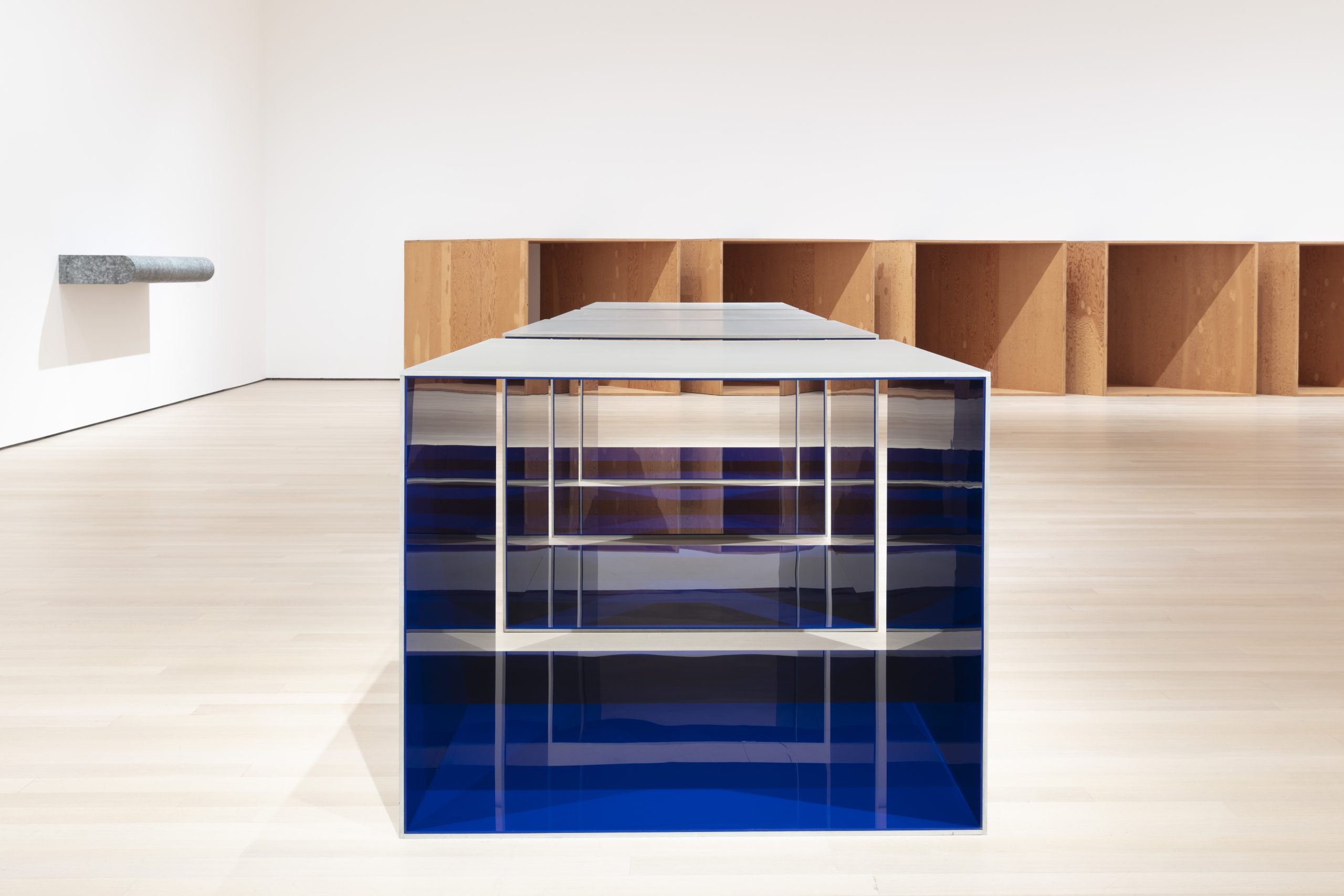 A square metal and plastic sculpture with a blue base in a museum gallery
