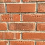 Close-up of a brick wall with the word "MEXICO" stamped upside down into some of the bricks