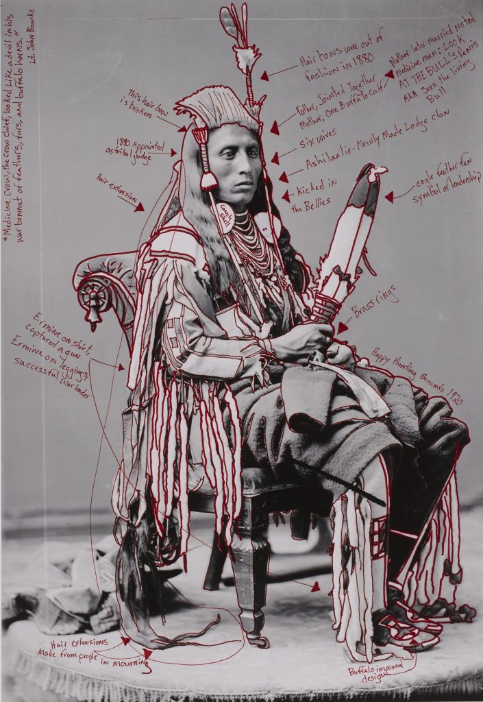 Black-and-white photograph of a seated Native American man on an ornate chair. The man's body and clothing, and the chair, are outlined in red, and various captions in red describe aspects of the photograph.