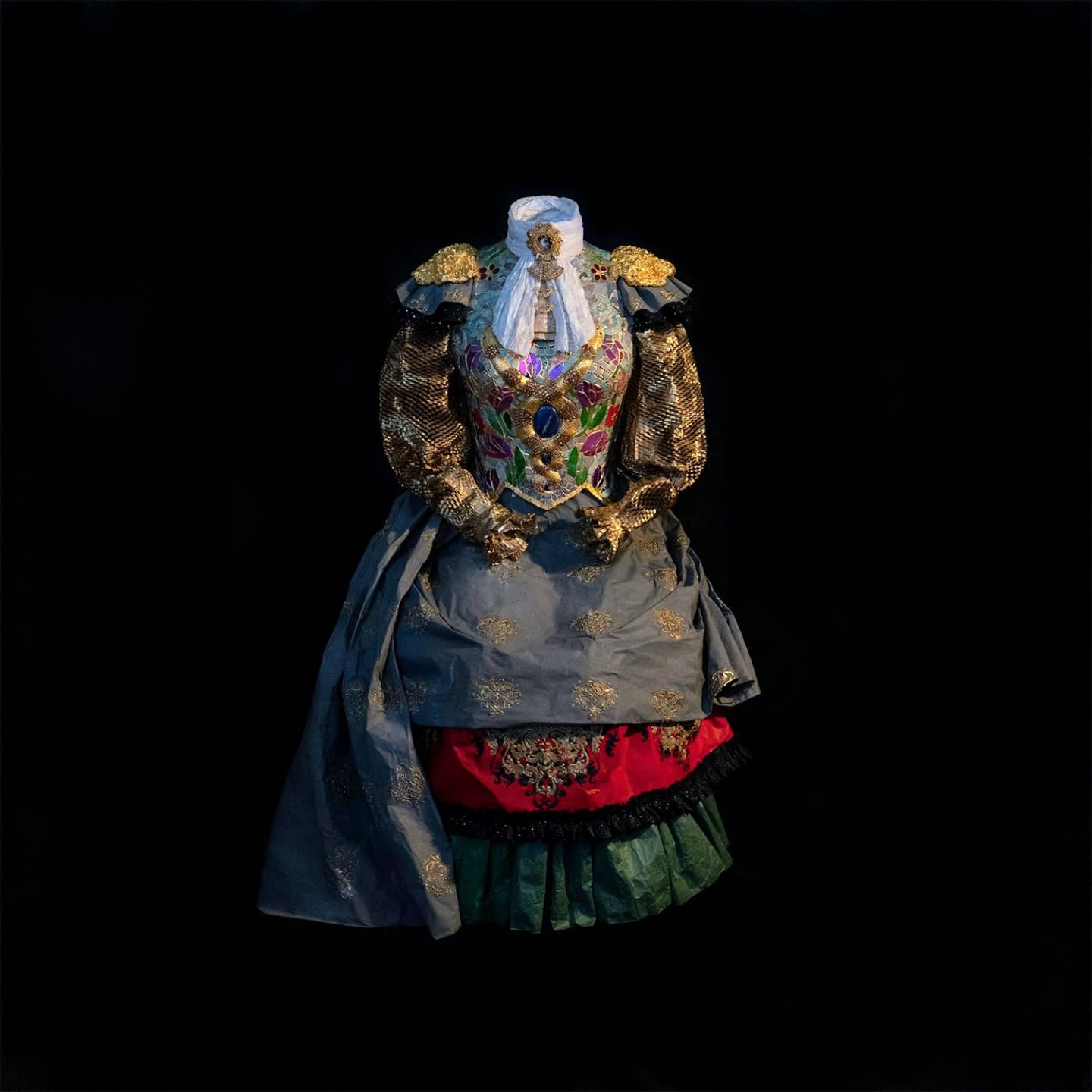 A headless mannikin dressed in ornate 19th-century women's clothing, set against a dark background.