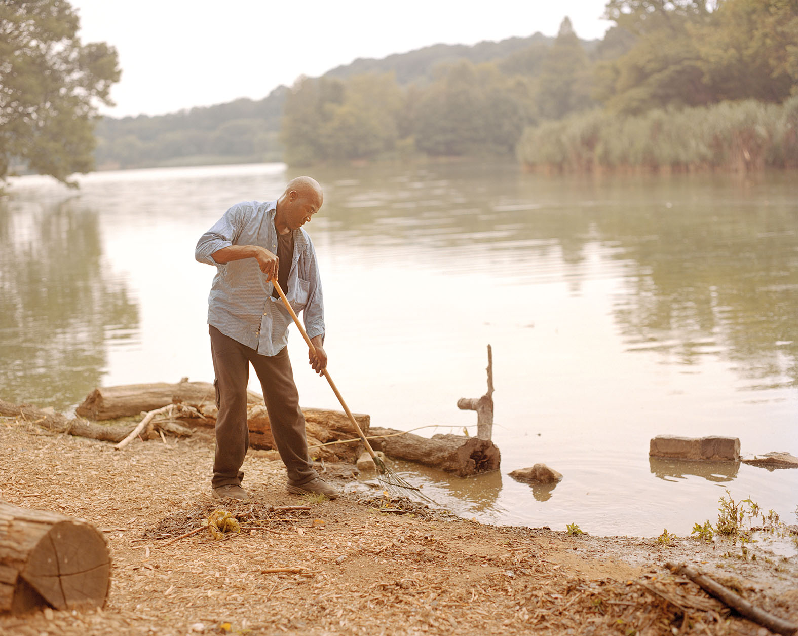 Color photograph of a man raking the edge of a body of water