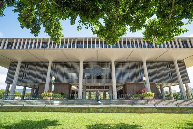 Postwar concrete building with first floor that is open to the elements and fronted with modern columns. There is a statue out front in the center.