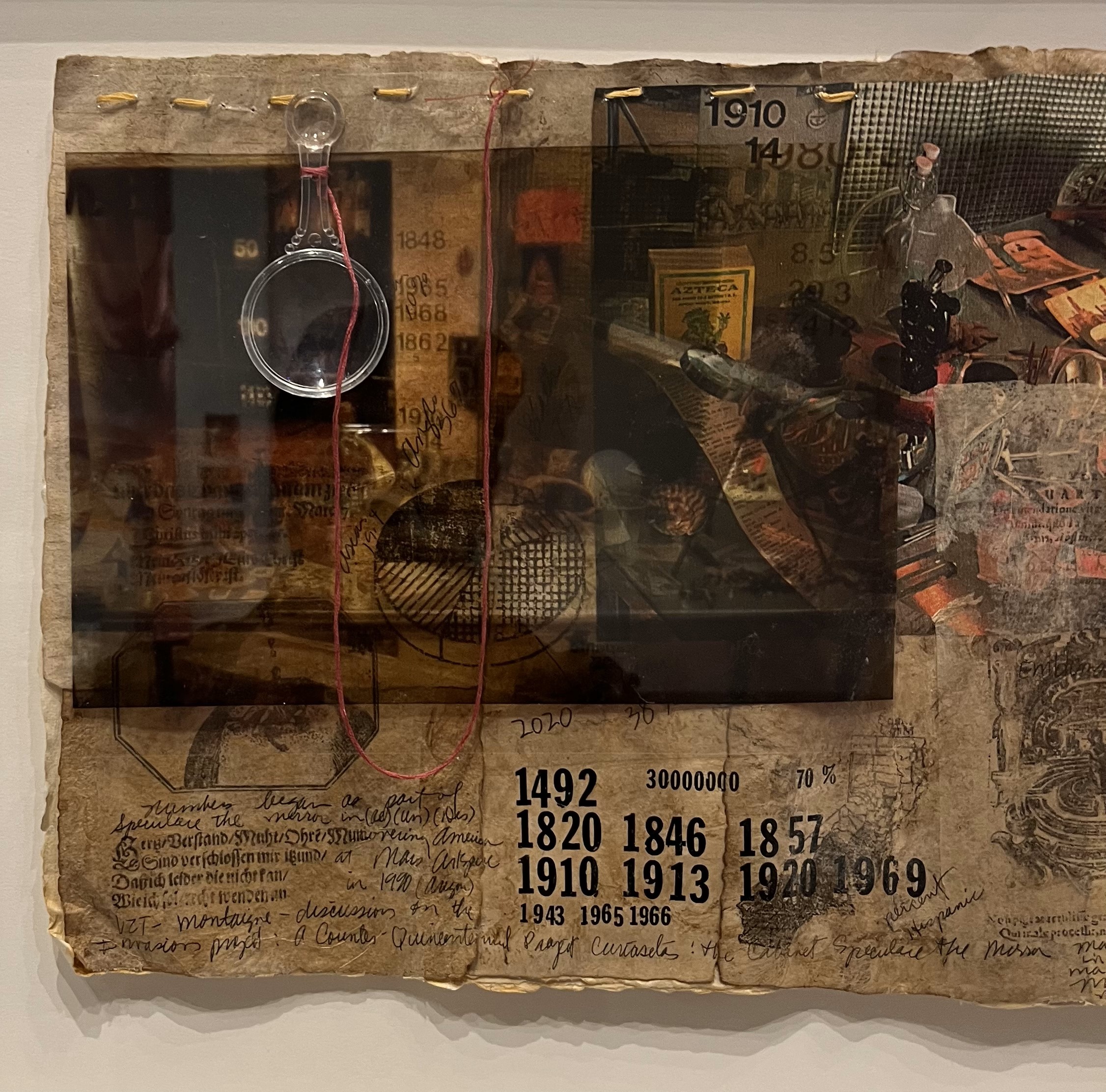 Collaged composition with small plastic magnifying glass hanging from the upper left. Printed at the bottom are the dates 1492, 1820, 1846, 1857, 1910, 1813, 1820, 1969, 1943, 1965, 1966