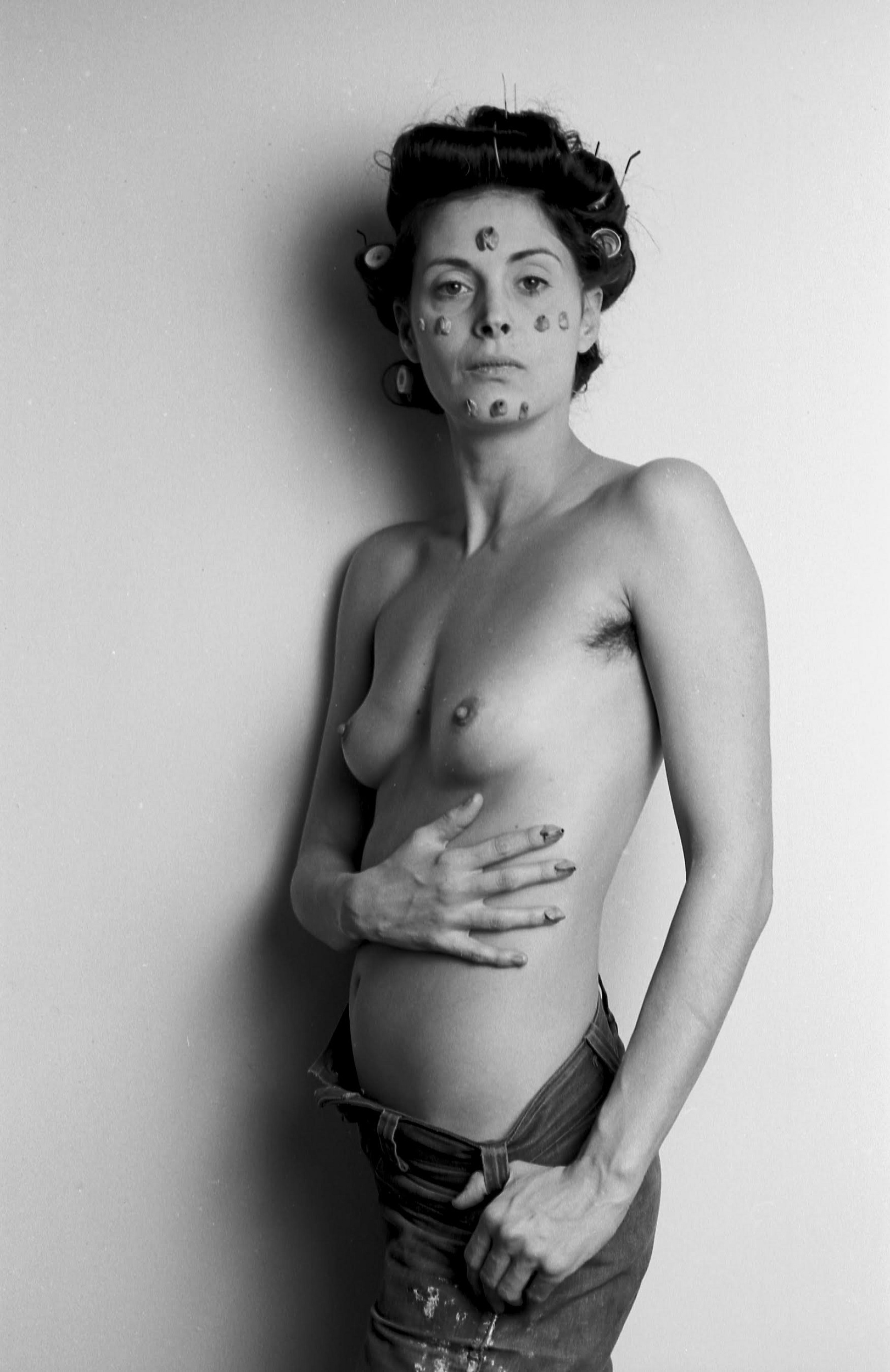 Black-and-white photograph of a woman nude from the waist up, with chunks of chewed bubble gum attached to her face and torso