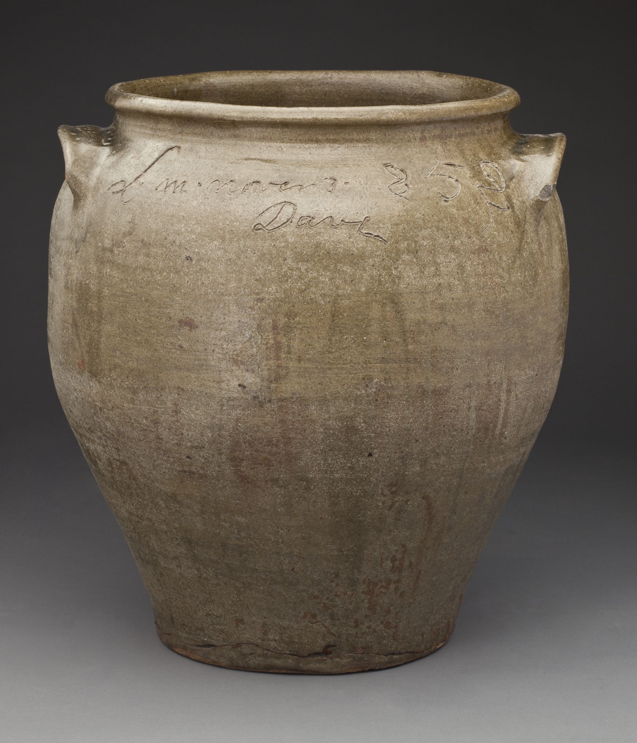 Ceramic vessel with a wide mouth and two spoon-shaped handles. The vessel is covered with a rough gray glaze. An inscription near the rim is mostly illegible but ends with "Dave."