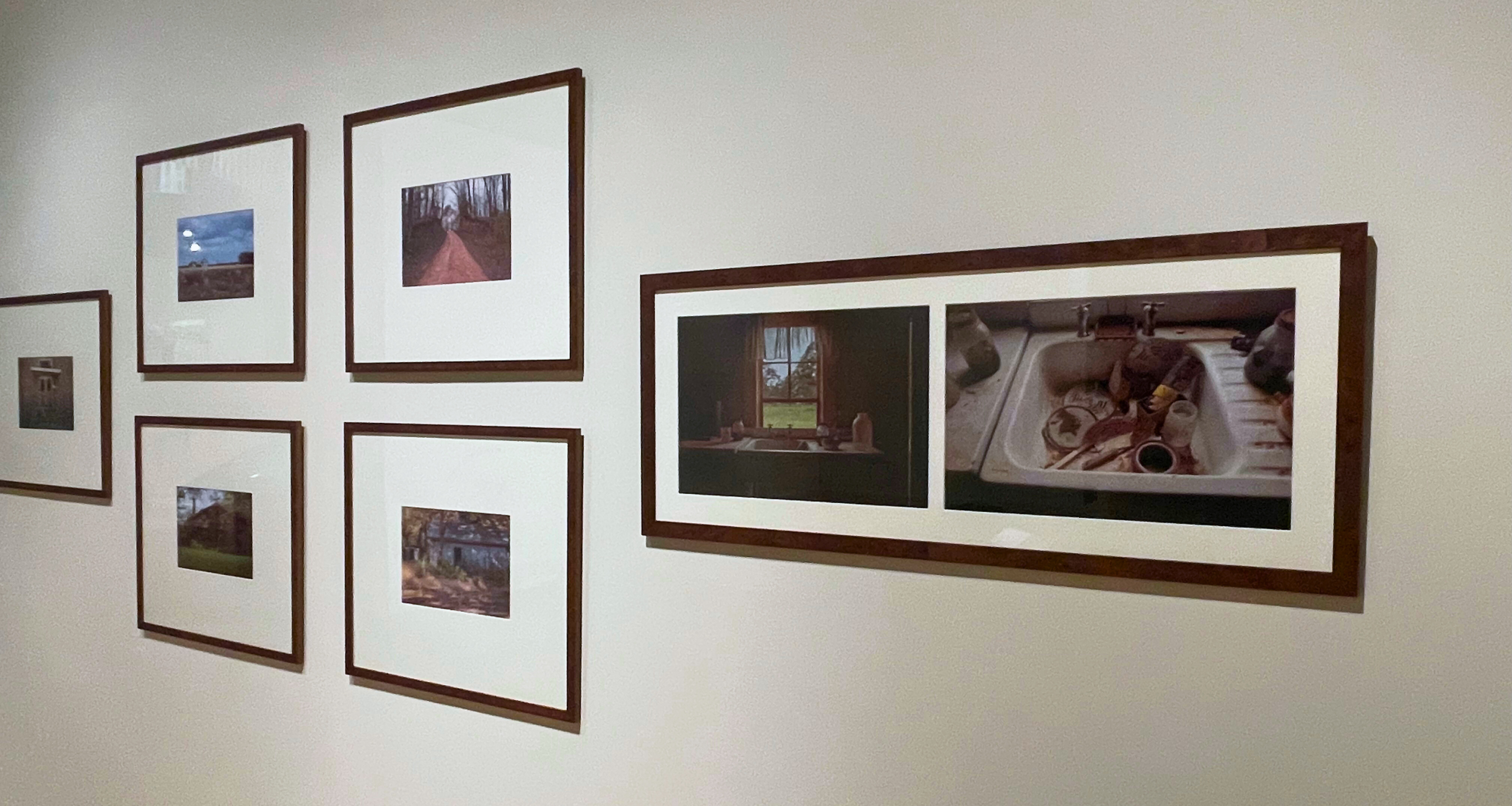 A gray-white wall hung with five framed photographic works of art.