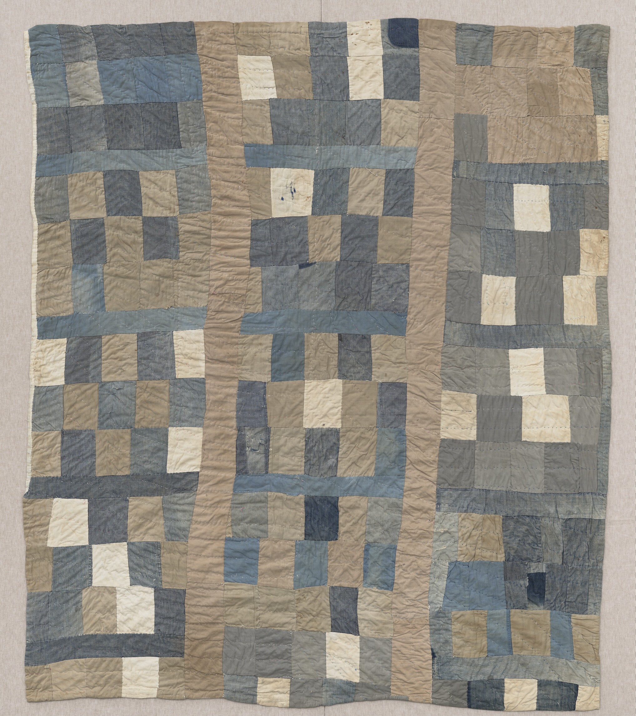 Quilt made of irregular blue, cream and beige pieced blocks