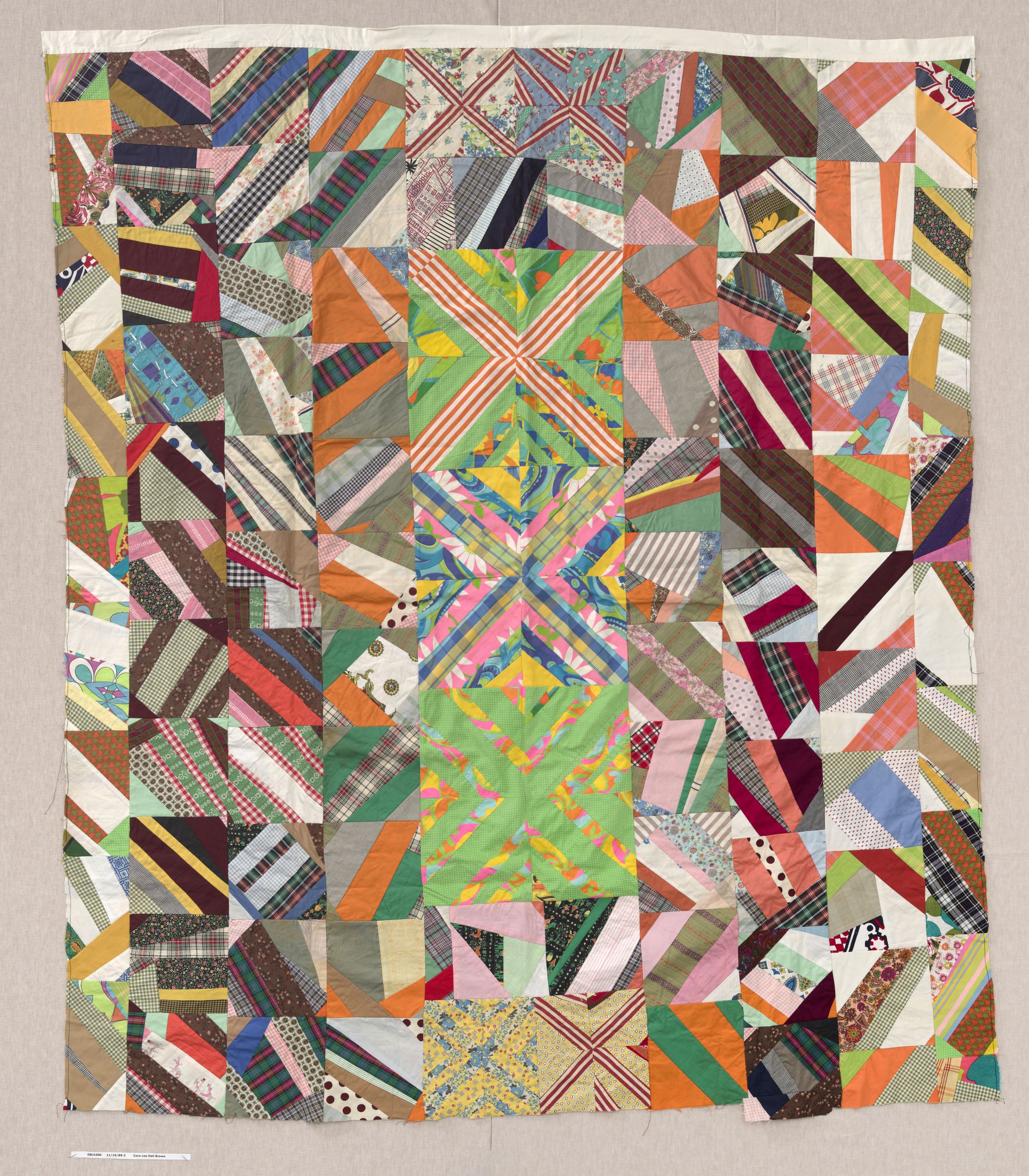 Colorful quilt made of piece blocks, each one composed of angled strips in a variety of patterns and colors.