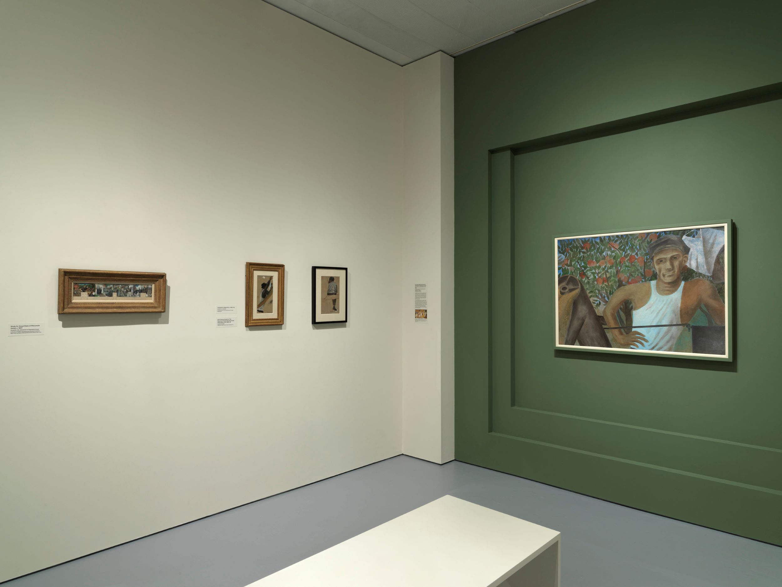 Interior of a museum gallery where two walls meet. On the left-hand wall, which is white, hang three small framed works of art. On the right-hand wall, which is green, hangs a large painting of a man in a sleeveless white undershirt, in front of a field of flowers.